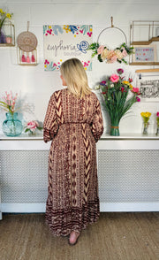 View from back of Tan patterned midi dress with v neckline and floaty sleeves