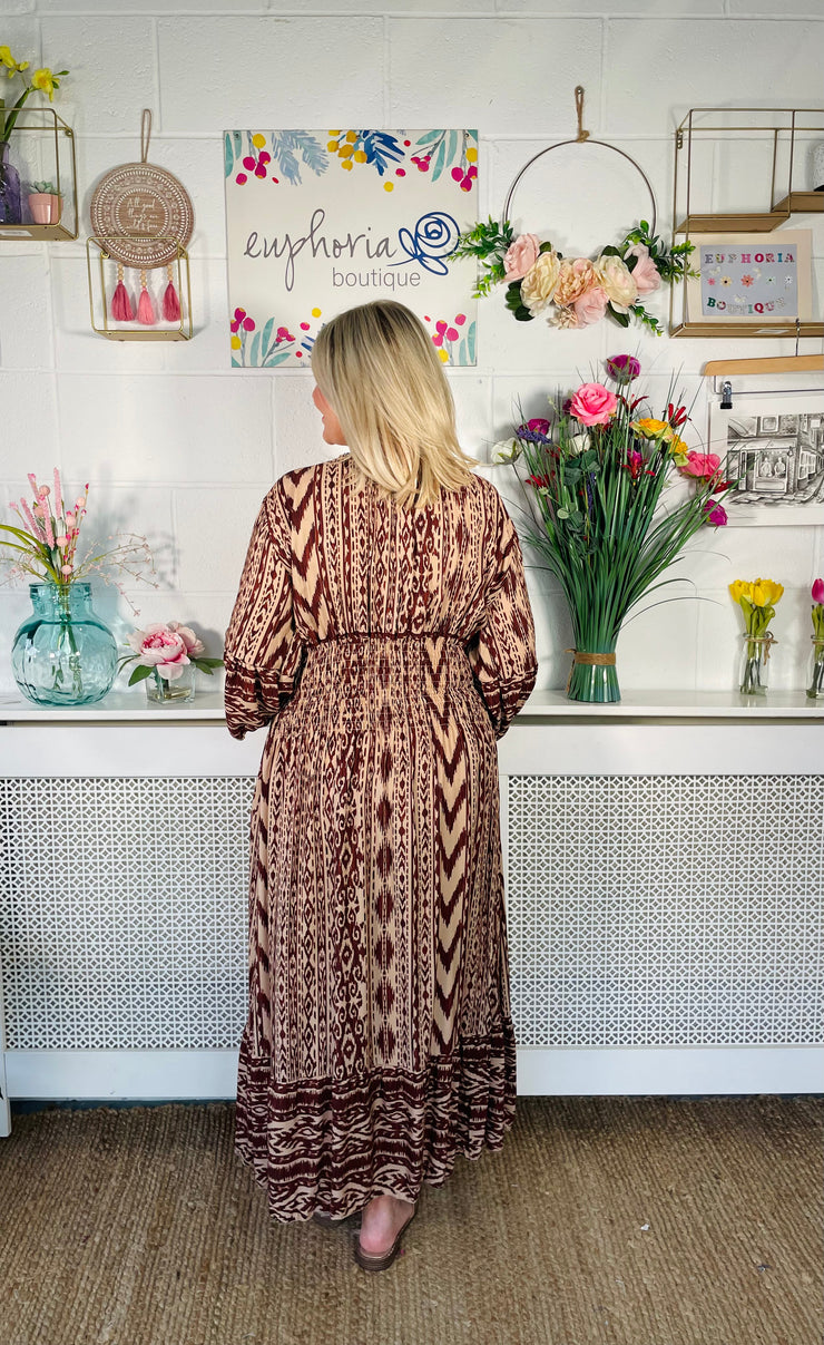 View from back of Tan patterned midi dress with v neckline and floaty sleeves